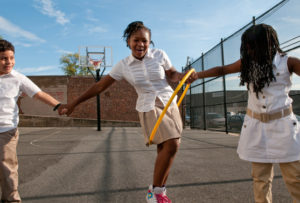 Children moving hula hoop while holding hands