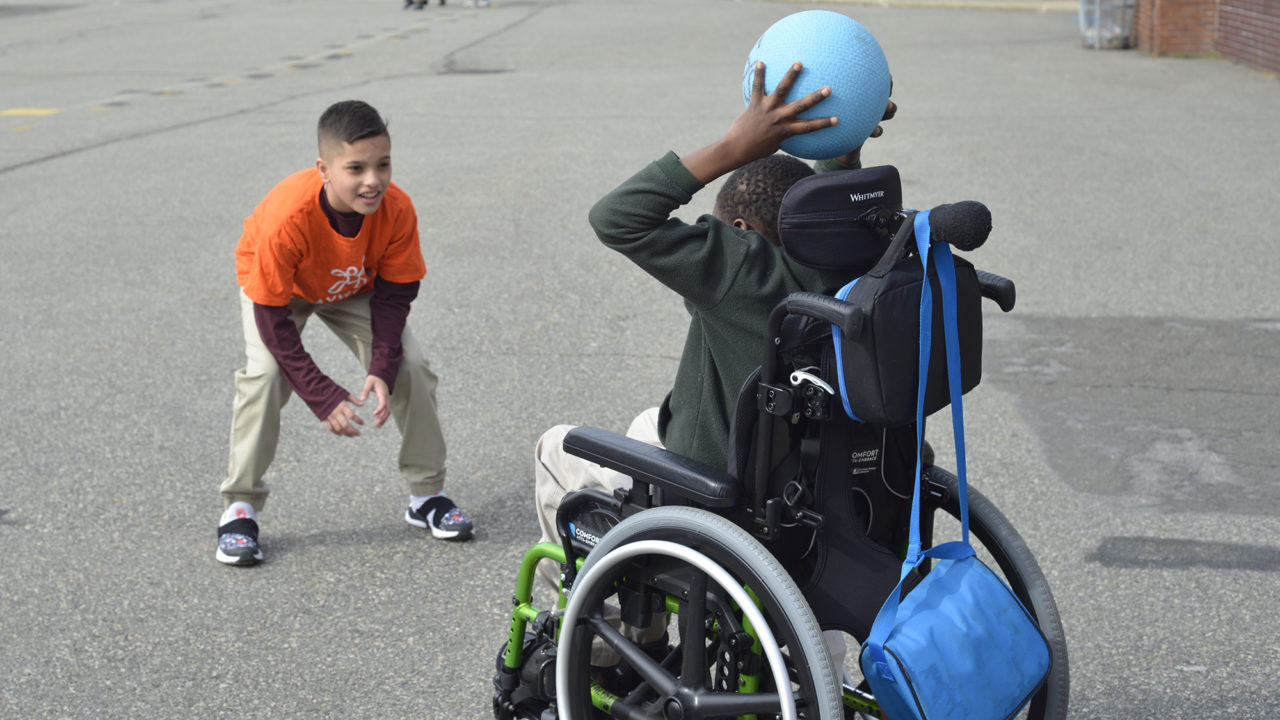 child in wheelchair throwing ball to another child