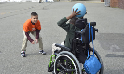 child in wheelchair throwing ball to another child