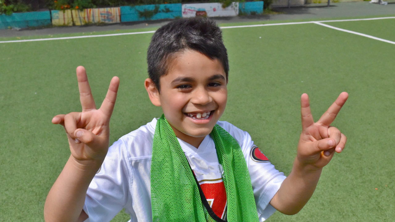 kid smiling and holding up peace signs