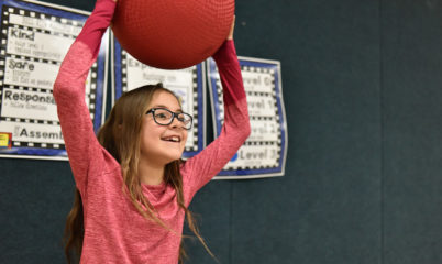 girl holding ball over head