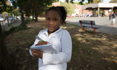 girl writing in notebook outdoors