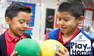 two kids holding balls in classroom