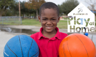 child holding two basketballs