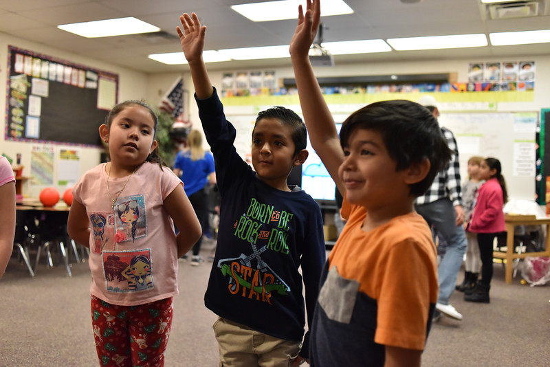 children raising their hands in classroom