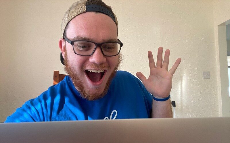 man holding up hand in front of computer