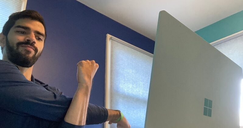 man stretching in front of laptop